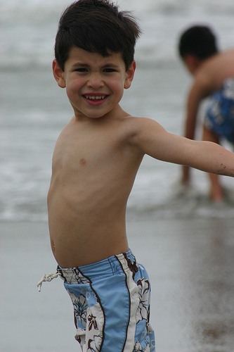 boy in his blue swim shorts at the beach